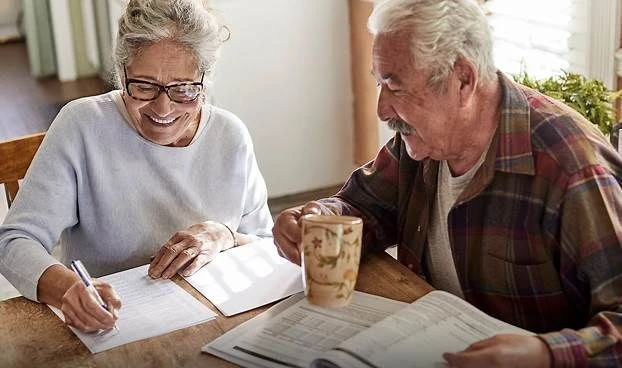 Senior couple reviewing final expense life insurance and mortgage protection documents at a kitchen table