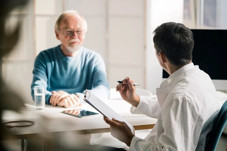 A financial advisor seated across from a senior at a desk, reviewing legal documents
